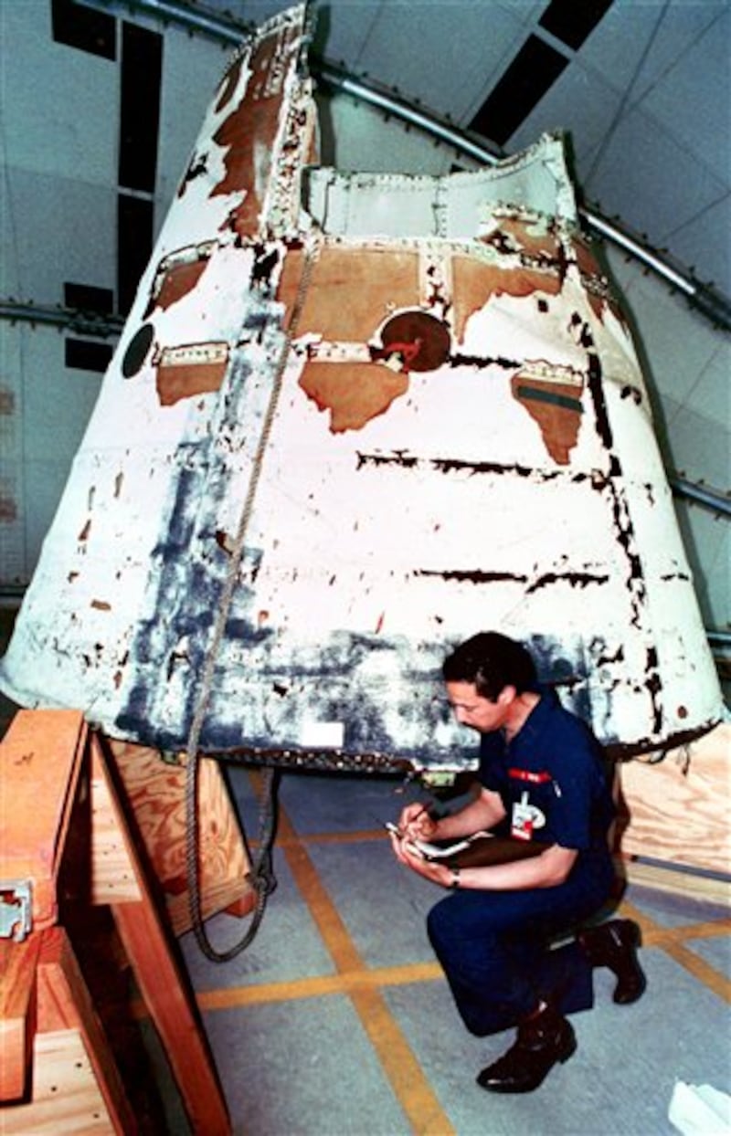 ADVANCE FOR USE TUESDAY, JULY 5, 2011 AND THEREAFTER - FILE - In this April 9, 1986 file picture, National Transportation Safety Board investigator John White kneels in front of the nose cone of the Challenger's right solid rocket booster at the Kennedy Space Center in Cape Canaveral, Fla. (AP Photo/Pool)